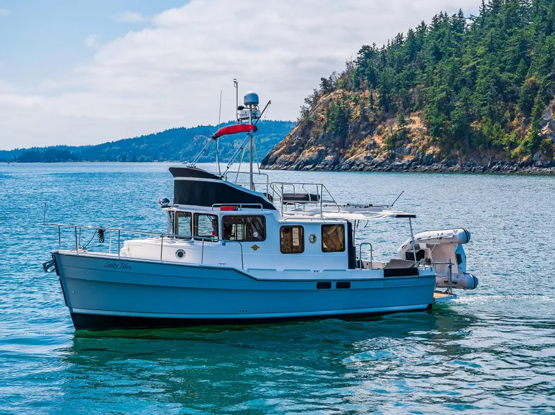 Slide: The Image of 2021 Ranger Tugs R-31 CB cruising near a forested coastline. - 9
