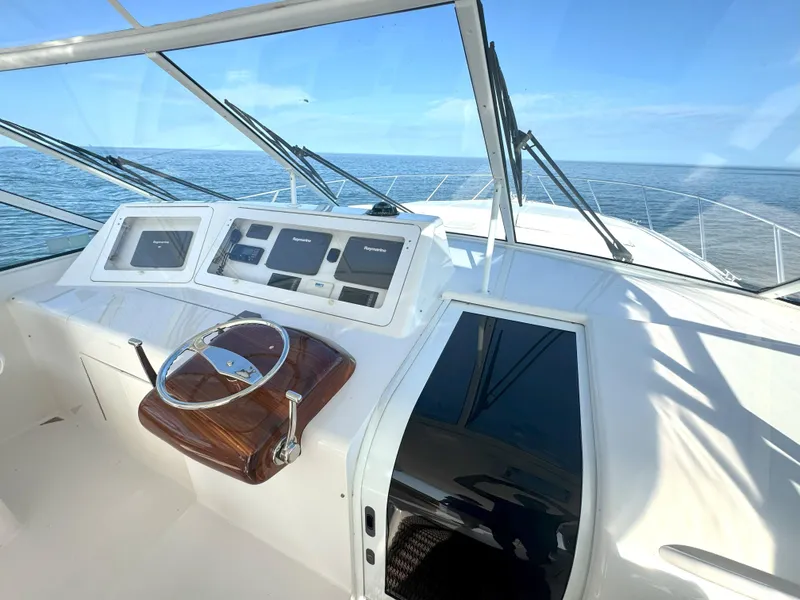 Slide: The Image of 2007 Viking 52 Open yacht helm with ocean view, featuring navigation instruments and wooden steering wheel. - 26