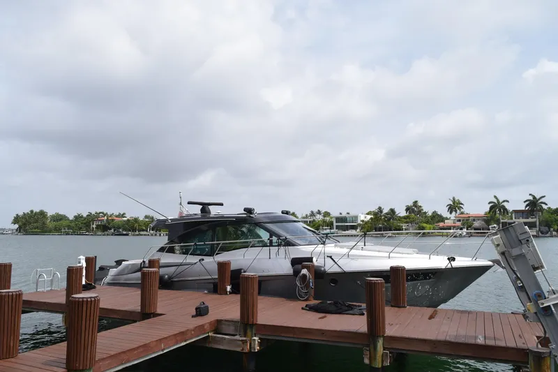 The Image of 2018 Cruisers Yachts 45 Cantius docked by waterfront homes under cloudy sky. - 0