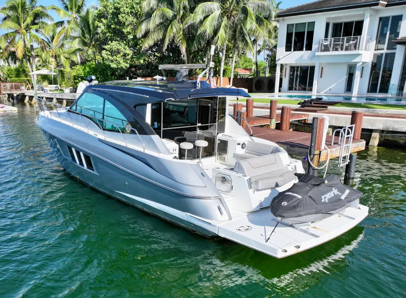 Slide: The Image of 2018 Cruisers Yachts 45 Cantius docked by a waterfront home, surrounded by palm trees. - 23