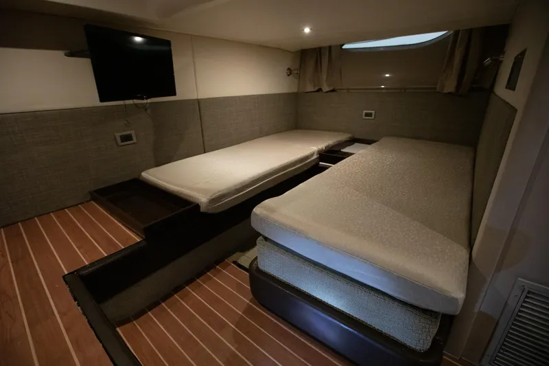 Slide: The Image of 2018 Sea Ray Sundancer 400 cabin interior with twin beds and a wall-mounted TV. - 17