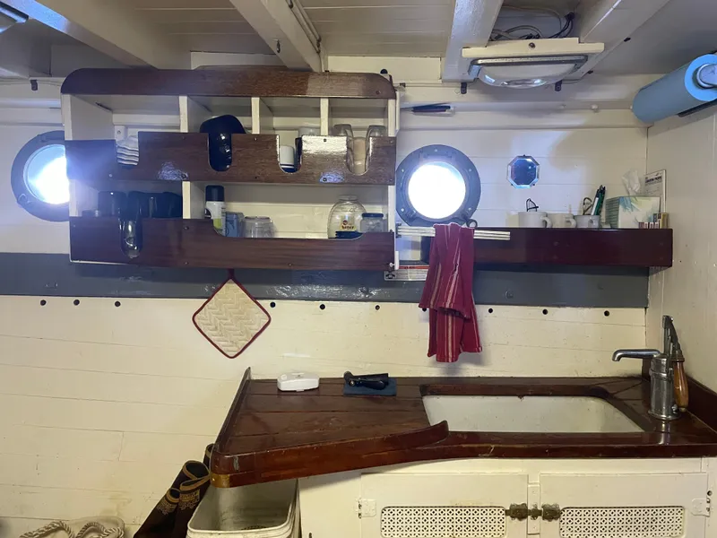 Slide: The Image of Vintage 1920 Blanchard Dunlin 42 boat kitchen with wooden shelves and porthole windows. - 10