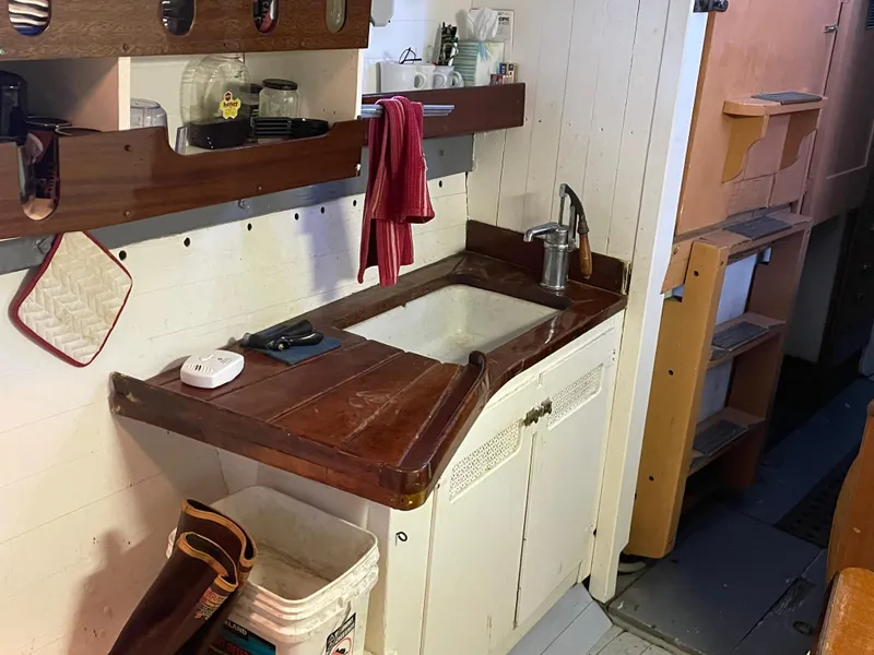 Slide: The Image of 1920 Blanchard Dunlin 42 boat kitchen with wooden countertop, sink, and storage shelves. - 12