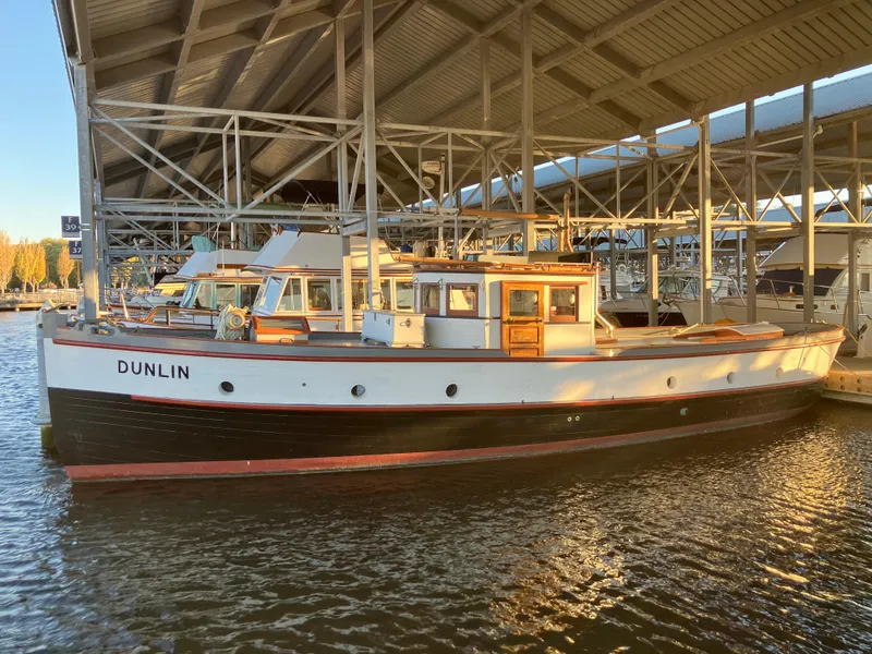 Slide: The Image of Vintage 1920 Blanchard Dunlin 42 boat docked under a marina shelter. - 2