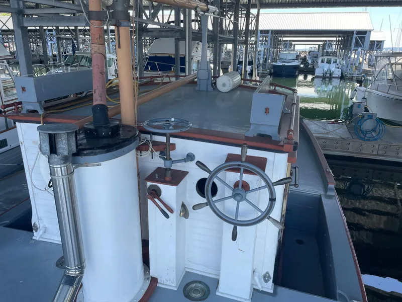 Slide: The Image of 1920 Blanchard Dunlin 42 boat docked in a marina, showcasing vintage steering wheel and deck. - 7