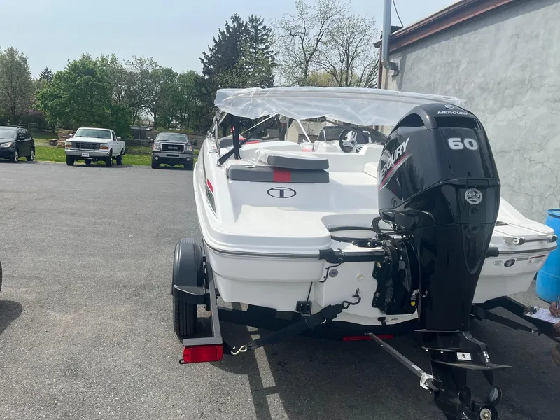Slide: The Image of 2025 Tahoe T16 boat with Mercury 60 engine on a trailer in a parking lot. - 2