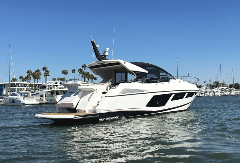 Slide: The Image of 2019 Sunseeker Predator 57 yacht cruising in a marina with palm trees and clear skies. - 6