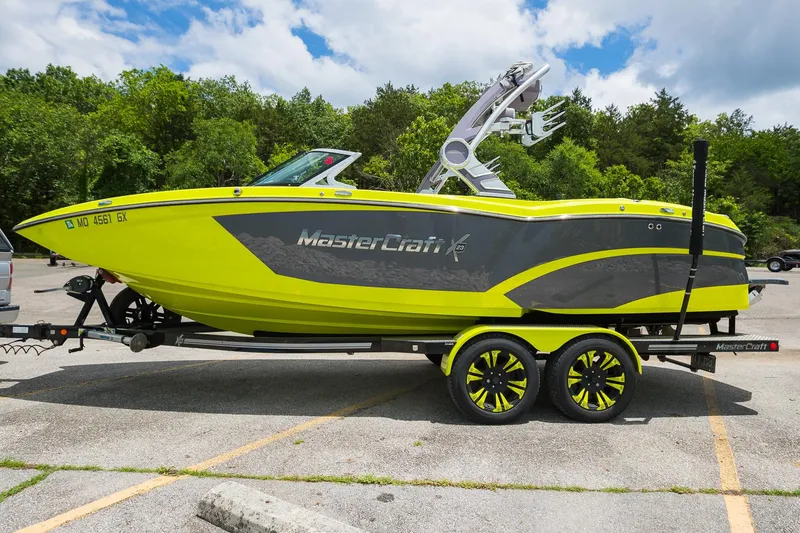 Slide: The Image of 2018 MasterCraft X23 boat in vibrant yellow on a trailer, parked outdoors. - 0