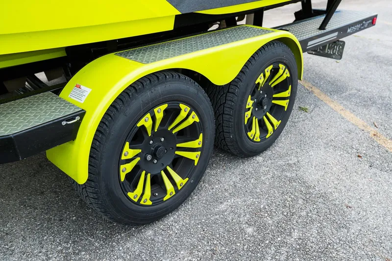 Slide: The Image of 2018 MasterCraft X23 trailer with vibrant yellow wheels and fenders on a textured surface. - 16