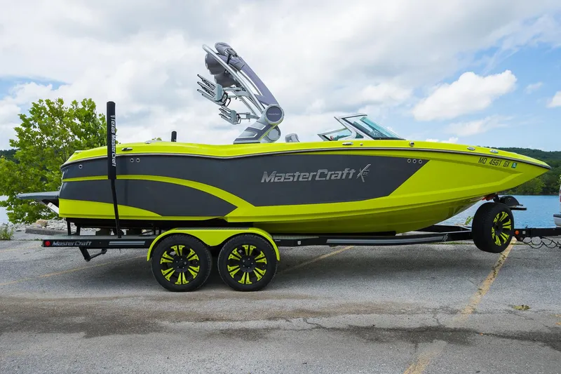 Slide: The Image of 2018 MasterCraft X23 boat on trailer, vibrant yellow and gray design, parked near a lake. - 22