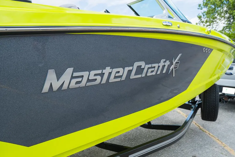 Slide: The Image of 2018 MasterCraft X23 boat with vibrant yellow and gray design on trailer. - 23