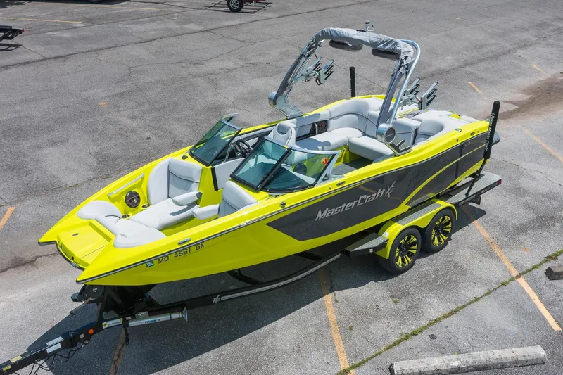 Slide: The Image of 2018 MasterCraft X23 boat in vibrant yellow, parked on a trailer in a lot. - 3