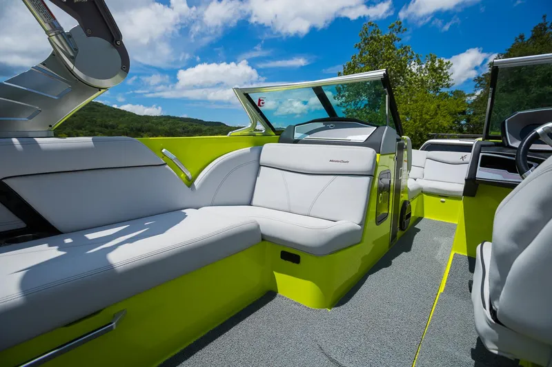 Slide: The Image of 2018 MasterCraft X23 boat interior with lime green accents and white seating under blue sky. - 36