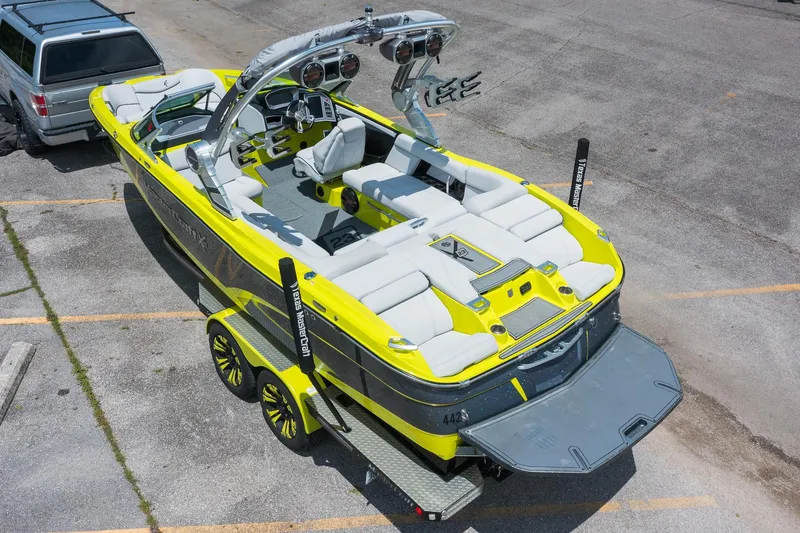 Slide: The Image of 2018 MasterCraft X23 boat in vibrant yellow, parked on a trailer in a lot. - 4
