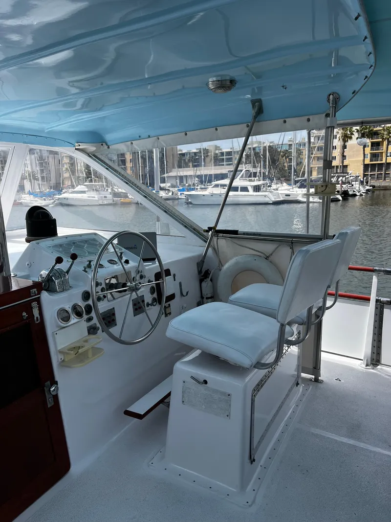 Slide: The Image of 1965 Hatteras 41 Twin Cabin helm with steering wheel, controls, and marina view. - 14