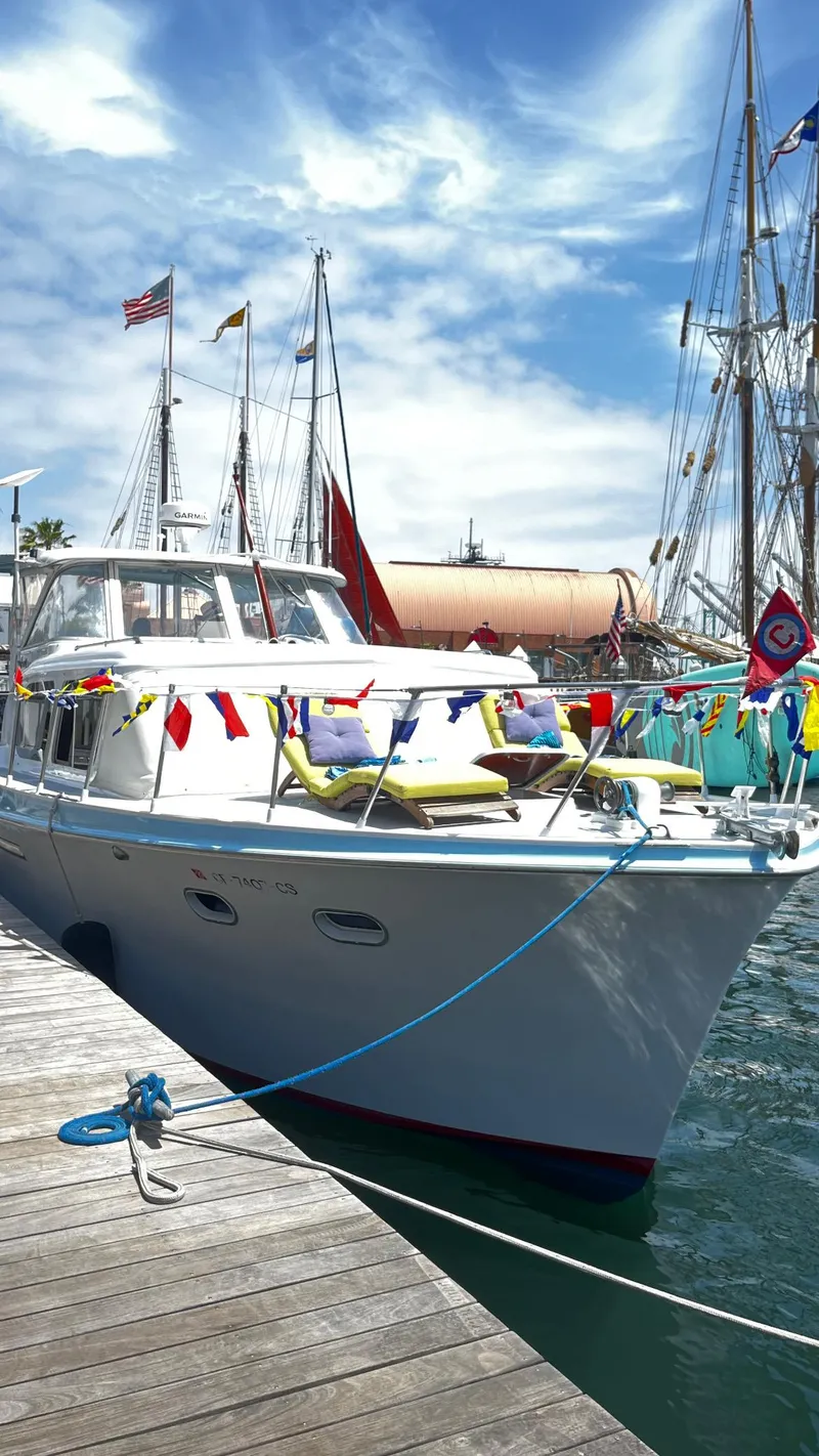 Slide: The Image of 1965 Hatteras 41 Twin Cabin yacht docked, adorned with colorful flags under a bright blue sky. - 3