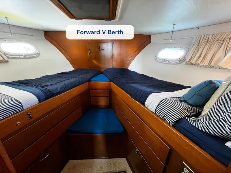 Slide: The Image of Forward V berth in 1965 Hatteras 41 Twin Cabin, featuring cozy bedding and wooden cabinetry. - 38