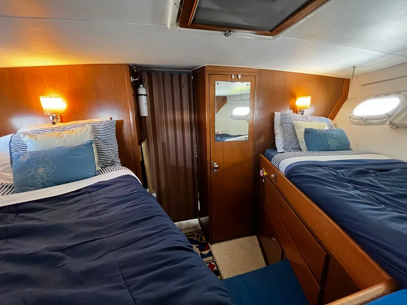 Slide: The Image of 1965 Hatteras 41 Twin Cabin interior with twin beds, wooden paneling, and nautical decor. - 39