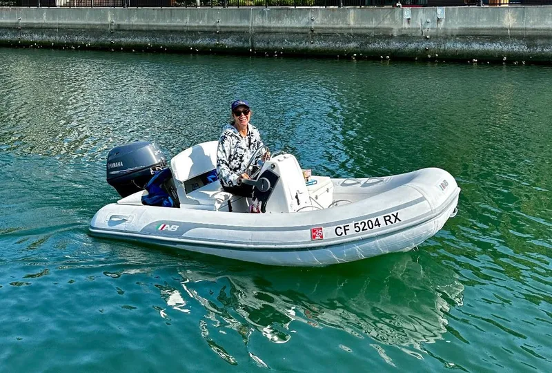 Slide: The Image of A person driving a small inflatable boat with a Yamaha motor on a calm waterway. - 48