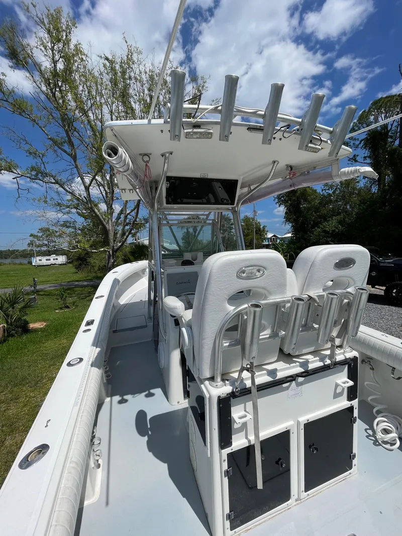Slide: The Image of 1998 Regulator 26 Classic boat with seating and rod holders, under a clear blue sky. - 12