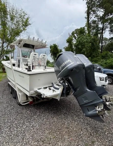 Slide: The Image of 1998 Regulator 26 Classic boat with Yamaha outboard motors on a gravel lot. - 6