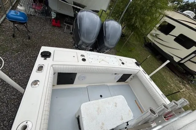 Slide: The Image of 1998 Regulator 26 Classic boat with dual outboard motors, parked near RV and equipment. - 8