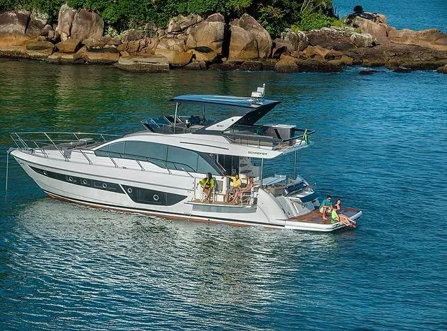 Slide: The Image of Luxurious 2026 Schaefer 600 yacht cruising near rocky shoreline with passengers enjoying the view. - 2