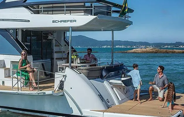 Slide: The Image of Luxury Schaefer 600 yacht with people enjoying a sunny day on the water, 2026 model. - 7