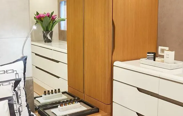 Slide: The Image of Modern bedroom with sleek white dressers, wooden wardrobe, and decorative flowers. Schaefer 660, 2025. - 19