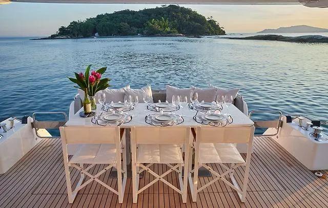 Slide: The Image of Luxury dining setup on Schaefer 660 yacht, 2025, with ocean view and island backdrop. - 36