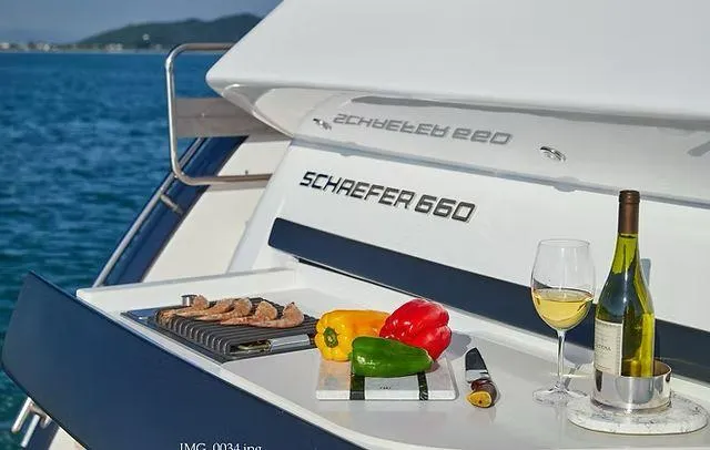 Slide: The Image of Luxury Schaefer 660 yacht with outdoor grill, wine, and colorful peppers, 2025 model. - 38