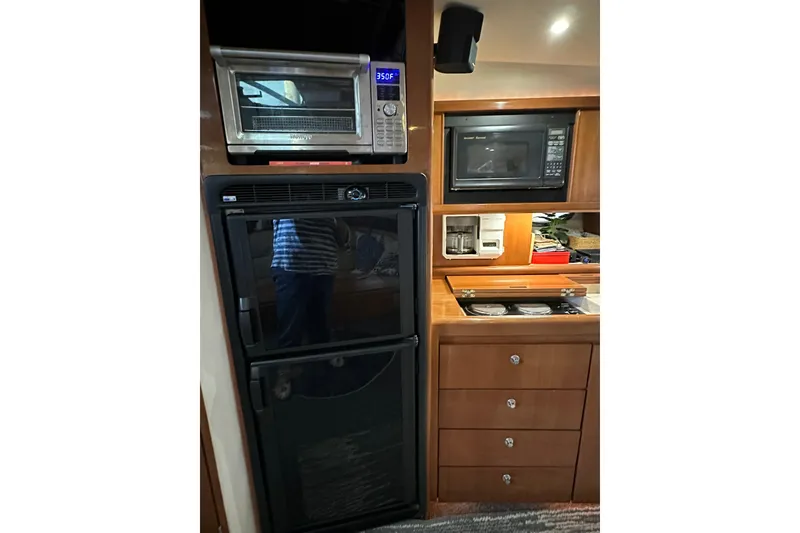 Slide: The Image of Kitchen area in a 1998 Trojan 440 Express yacht with appliances and storage. - 13