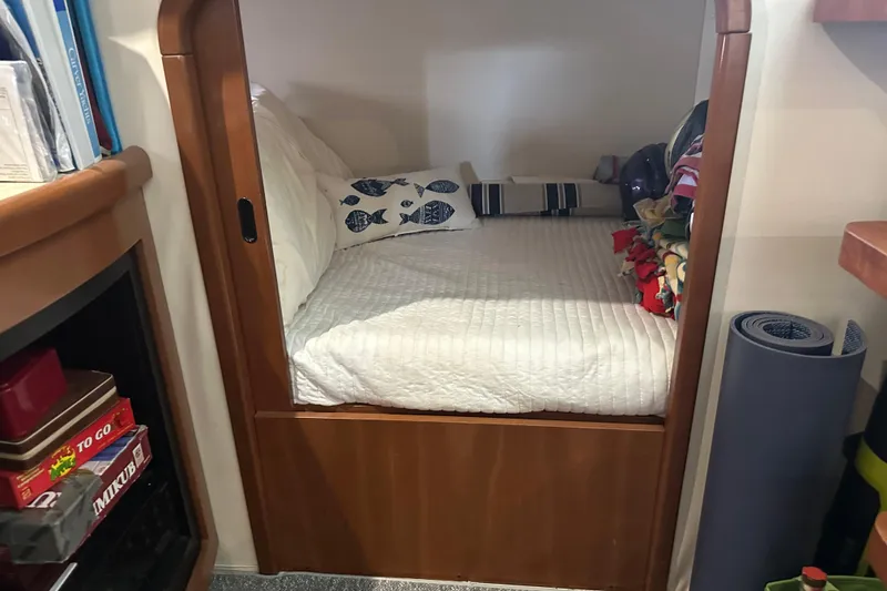 Slide: The Image of Cozy cabin bed in a 1998 Trojan 440 Express yacht, featuring nautical-themed pillows. - 14