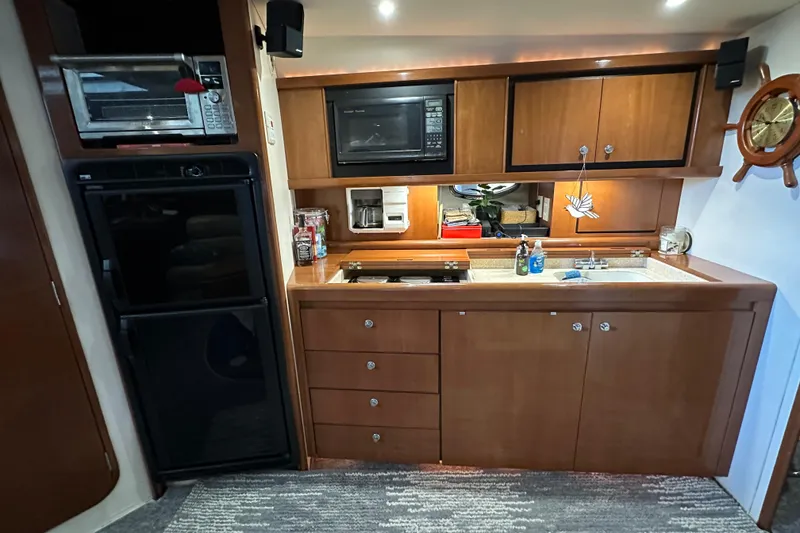 Slide: The Image of Kitchen area of a 1998 Trojan 440 Express yacht with wooden cabinets and appliances. - 2
