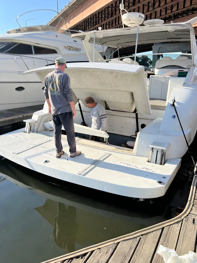 Slide: The Image of Two people working on a 1998 Trojan 440 Express yacht at a marina. - 37