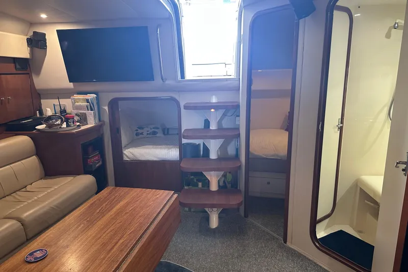 Slide: The Image of Interior of a 1998 Trojan 440 Express yacht with seating, TV, and sleeping quarters. - 8