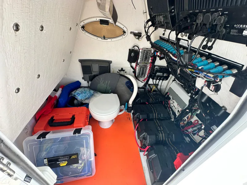 Slide: The Image of Interior of 2023 Twin Vee 340 GFX CC boat, featuring storage, wiring, and a compact toilet. - 14