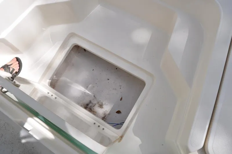 Slide: The Image of 2017 Skeeter SX 210 boat storage compartment with open hatch and visible debris. - 32