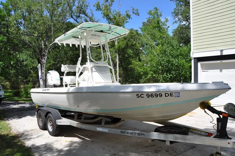 Slide: The Image of 2017 Skeeter SX 210 boat on trailer, parked in driveway, surrounded by trees. - 4