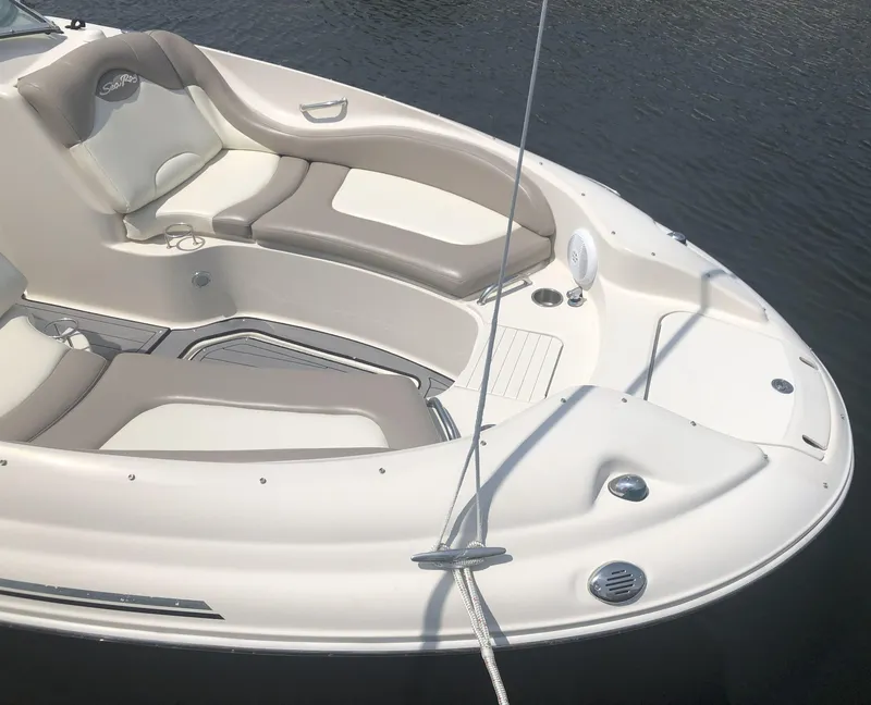Slide: The Image of 2006 Sea Ray 270 Sundeck boat interior with beige seating, docked on calm water. - 13