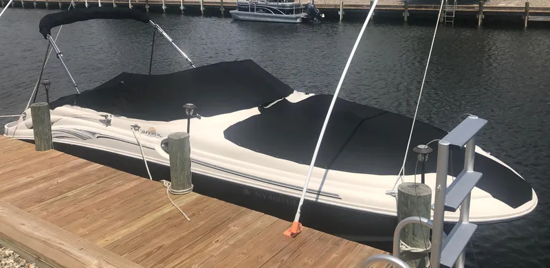 Slide: The Image of 2006 Sea Ray 270 Sundeck boat docked with black cover, calm water background. - 16