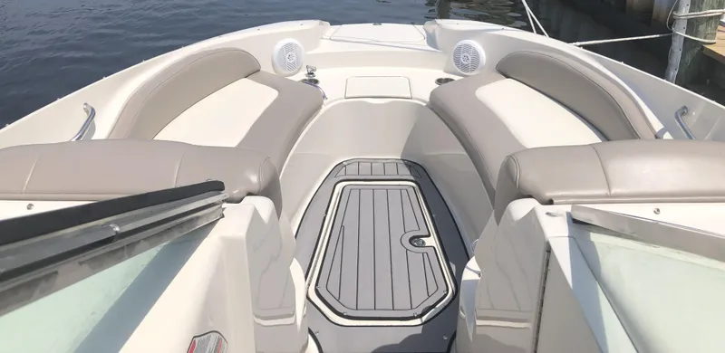 Slide: The Image of 2006 Sea Ray 270 Sundeck interior with cushioned seating and deck, docked by water. - 9