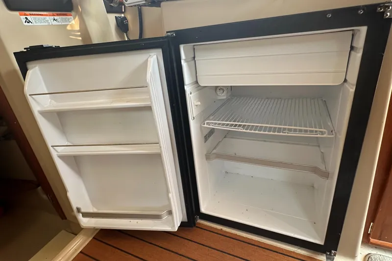Slide: The Image of Open refrigerator inside 2019 Ranger Tugs R-23 boat, showing empty shelves and freezer compartment. - 11