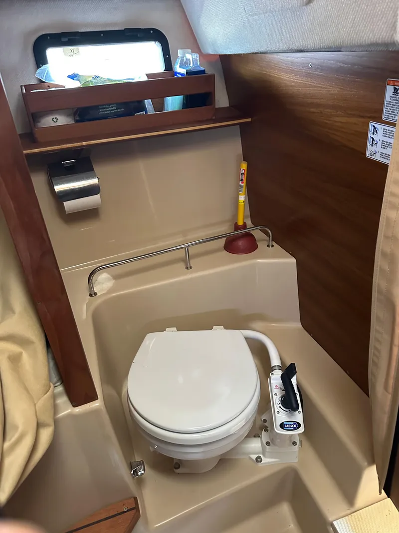 Slide: The Image of 2019 Ranger Tugs R-23 boat bathroom with toilet, plunger, and window. - 13