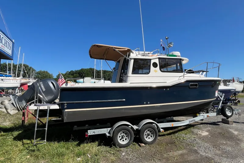 Slide: The Image of 2019 Ranger Tugs R-23 boat on trailer, blue hull, parked outdoors under clear sky. - 25