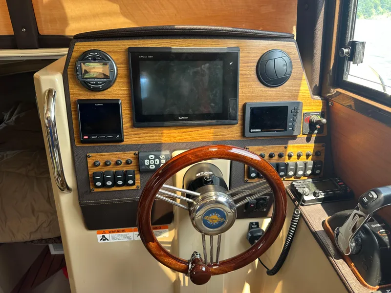 Slide: The Image of 2019 Ranger Tugs R-23 helm with wooden dashboard, steering wheel, and navigation controls. - 3