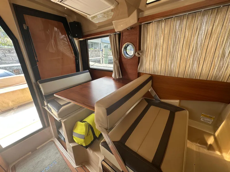 Slide: The Image of 2019 Ranger Tugs R-23 interior with dining area, wood table, and cushioned seating. - 7