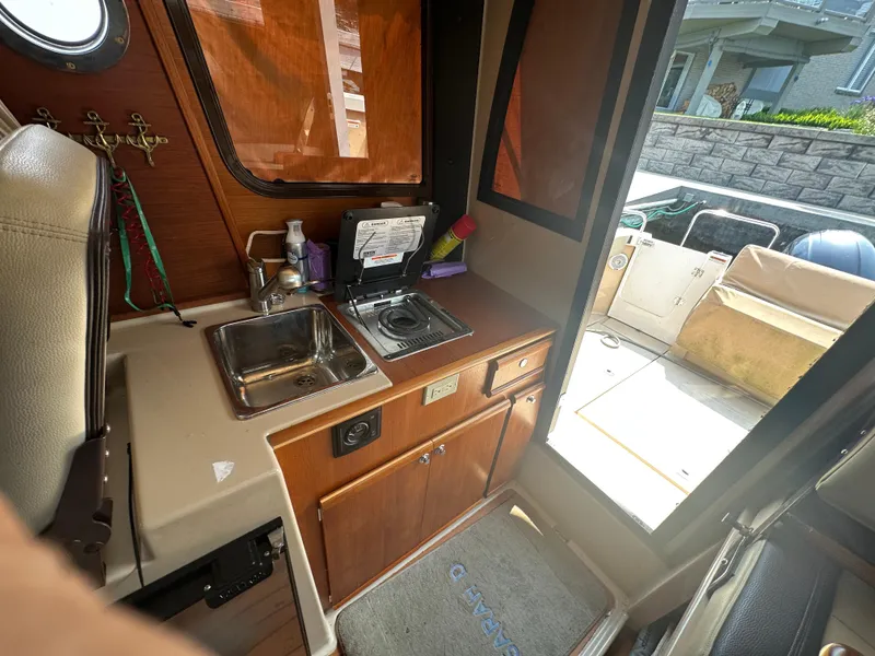 Slide: The Image of 2019 Ranger Tugs R-23 boat interior with kitchenette, sink, and outdoor view. - 9