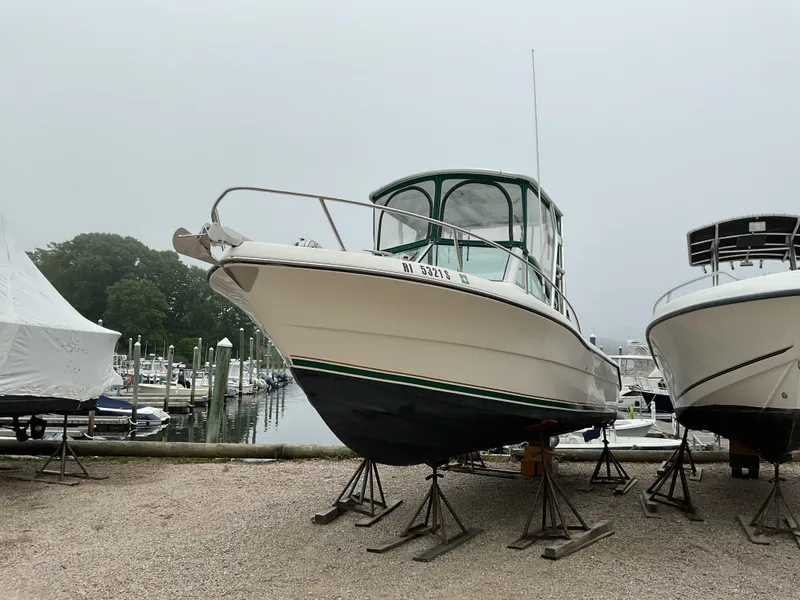 The Image of 1997 Pursuit 2460 Denali boat on stands at marina, overcast day. - 1