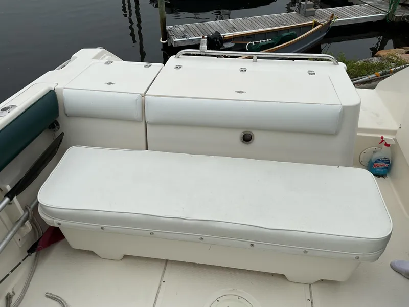 Slide: The Image of 1997 Pursuit 2460 Denali boat interior with white seating and storage compartments. - 5